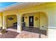 Inviting front porch with stucco columns, brick flooring, seating area, and unique entryway decor at 4508 Mangrove Point Rd, Bradenton, FL 34210