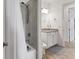 Bright bathroom with white tile shower, white vanity with grey top, and wood-look tile floor at 4524 Baltry Ct, Bradenton, FL 34211