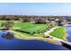 Picturesque aerial view of the lush golf course with a serene lake, bridge, and golfers enjoying a sunny day at 4524 Baltry Ct, Bradenton, FL 34211