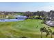 Picturesque aerial view of the lush golf course with a serene lake, bridge, and golfers enjoying a sunny day at 4524 Baltry Ct, Bradenton, FL 34211