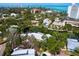 Gorgeous aerial view of a lakeside property with a pool, surrounded by mature trees and serene water at 4830 Estrada De Costa, Sarasota, FL 34242