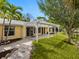Yellow house with a white pergola overlooking a pond with a well manicured lawn at 4830 Estrada De Costa, Sarasota, FL 34242