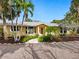 Charming single-story home features lush landscaping with mature palms and a welcoming walkway to the front door at 4830 Estrada De Costa, Sarasota, FL 34242