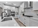 Modern kitchen with stainless steel appliances, a herringbone backsplash, and a large sink and faucet at 4869 Antrim Dr, Sarasota, FL 34240