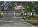 Beautifully landscaped home with a three-car garage, colorful plants, and manicured lawn at dusk at 5103 Twin Creeks Dr, Valrico, FL 33596