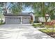 Beautifully landscaped home with a three-car garage, colorful plants, and manicured lawn at 5103 Twin Creeks Dr, Valrico, FL 33596