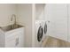 Laundry room featuring a sink, storage cabinets, and a modern washer and dryer at 5103 Twin Creeks Dr, Valrico, FL 33596