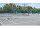 Well-maintained tennis courts with green fencing and shaded seating area for players at 5103 Twin Creeks Dr, Valrico, FL 33596