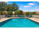 Community pool with a fence, lounge chairs, tables, and umbrellas for resident's enjoyment at 5609 Spanish Point Ct, Palmetto, FL 34221