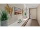 Inviting hallway with coastal-inspired decor, a beach painting, and lush greenery accents at 5806 Gulf Dr # 201, Holmes Beach, FL 34217