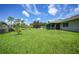 Expansive backyard with lush green lawn, mature trees, and a screened-in lanai, perfect for outdoor enjoyment at 590 Ridgewood Nw St, Port Charlotte, FL 33952