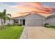 Charming single-story home featuring a well-manicured lawn and two-car garage, bathed in the warm hues of a vibrant sunset at 5958 164Th E Ave, Parrish, FL 34219