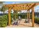 Relax in the charming seating area under a wooden pergola, surrounded by lush landscaping at 5958 164Th E Ave, Parrish, FL 34219