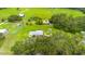 Wide aerial shot shows a home surrounded by lush greenery, complemented by a pool and outbuildings at 5981 Jim Davis Rd, Parrish, FL 34219