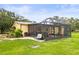 The backyard shows the outdoor living space with a screened in porch and lush landscaping at 5981 Jim Davis Rd, Parrish, FL 34219