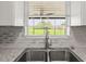 Double stainless steel kitchen sink with modern faucet and granite countertops overlooks a green lawn at 5981 Jim Davis Rd, Parrish, FL 34219