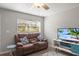 Cozy living room with a loveseat, TV, ceiling fan, and natural light from window at 5981 Jim Davis Rd, Parrish, FL 34219