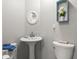 Clean and bright powder room featuring a pedestal sink, round mirror, and modern fixtures at 5981 Jim Davis Rd, Parrish, FL 34219