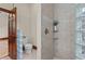 Bathroom featuring tiled shower with glass block window, toilet, and wooden door to the bedroom at 7025 Saddle Creek Cir, Sarasota, FL 34241