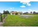 Wide shot of single story home with well-maintained lawn and adjacent buildings with red tile roof at 7025 Saddle Creek Cir, Sarasota, FL 34241
