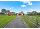 Exterior view of a well-maintained home with a long driveway and lush green lawn at 7025 Saddle Creek Cir, Sarasota, FL 34241