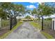 A gated entry leads to a large home with mature trees and manicured landscaping at 7025 Saddle Creek Cir, Sarasota, FL 34241