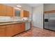 Bright kitchen features terracotta floors, white appliances, wooden cabinets, a double sink and backyard view at 7025 Saddle Creek Cir, Sarasota, FL 34241