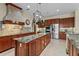 Gourmet kitchen with stainless steel appliances, mosaic backsplash, and an island with seating at 7025 Saddle Creek Cir, Sarasota, FL 34241