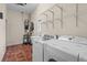 Functional laundry room with modern washer and dryer units, storage shelves, and tile flooring at 7025 Saddle Creek Cir, Sarasota, FL 34241