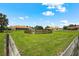 Spacious green riding area with wooden fence and multiple houses in the background under a bright blue sky at 7025 Saddle Creek Cir, Sarasota, FL 34241