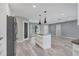 Open living room with white kitchen island and gray plank flooring throughout the living space at 7442 N Leewynn Dr, Sarasota, FL 34240