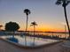 Waterfront pool view with palm trees and serene sunset, inviting relaxation and leisure at 767 John Ringling Blvd # 25, Sarasota, FL 34236