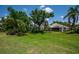 Expansive backyard with lush greenery, tropical trees, and a view of the home's exterior at 7952 Hampton Ct, University Park, FL 34201
