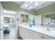 Bathroom featuring a double sink vanity with white cabinets, large mirror, and access to bedroom and shower at 8579 54Th Avenue E Cir, Bradenton, FL 34211