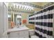 Bathroom showcasing a vanity with framed mirror, lighting, and a shower/tub combo with striped curtains at 8579 54Th Avenue E Cir, Bradenton, FL 34211