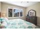 Comfortable bedroom featuring a dresser, window, and a king-size bed with blue and white tropical pattern bedding at 8579 54Th Avenue E Cir, Bradenton, FL 34211