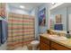 Cozy bathroom with decorative shower curtain, neutral walls, vanity with sink, and a lovely seascape painting at 8937 Excelsior Loop, Venice, FL 34293