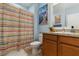 Well-lit bathroom featuring a colorful shower curtain, neutral walls, and a decorative mirror above the vanity at 8937 Excelsior Loop, Venice, FL 34293