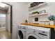 Functional laundry room with stacked washer and dryer, built-in shelves, and decorative accents for added appeal at 8937 Excelsior Loop, Venice, FL 34293