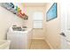 Bright laundry room with white washer and dryer, overhead shelving, tiled flooring, and a window at 11324 77Th E St, Parrish, FL 34219