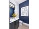 Powder room with shaker cabinets, stone countertops, statement art, and bold blue walls at 1162 Blue Shell Loop, Sarasota, FL 34240
