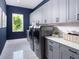 Modern laundry room with gray shaker cabinets, stainless steel appliances, and natural light from the window at 1162 Blue Shell Loop, Sarasota, FL 34240