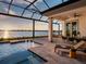 Luxurious outdoor patio with a pool, dining area, lounge chairs, and a stunning waterfront view at sunset at 1162 Blue Shell Loop, Sarasota, FL 34240