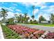 Grand entrance to Boca Royale Golf & Country Club, featuring vibrant floral landscaping and a gated entry for security at 1301 Backspin Dr, Englewood, FL 34223