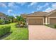 Inviting single-story home with lush landscaping, a brick driveway, and a two-car garage for convenient parking at 1301 Backspin Dr, Englewood, FL 34223