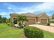 Charming home featuring a three-car garage, well-manicured lawn, and lush tropical landscaping at 1301 Backspin Dr, Englewood, FL 34223