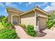 Home exterior featuring a two-car garage, neatly trimmed landscaping, and brick walkway to the front door at 1301 Backspin Dr, Englewood, FL 34223