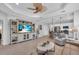 Open-concept living room with a large TV, neutral colors, and views of the kitchen and lanai at 1301 Backspin Dr, Englewood, FL 34223