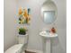 Stylish half bathroom with pedestal sink, oval mirror, and patterned wall art at 13133 Bayberry Way, Parrish, FL 34219