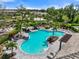 An aerial shot showcasing a sparkling community pool surrounded by lounge chairs, palm trees, and lush landscaping at 15316 Shady Palms Ln, Nokomis, FL 34275